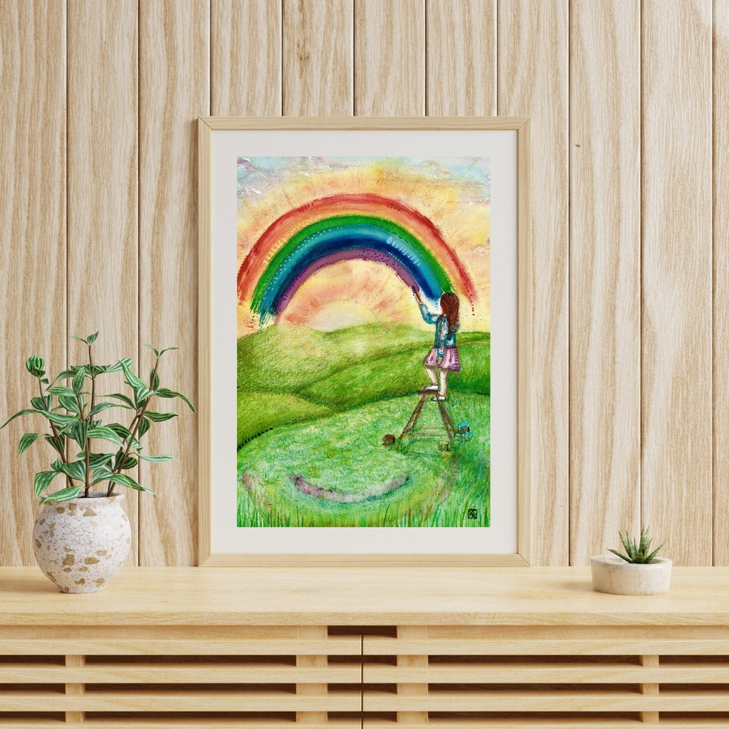 Der farbenfrohe Kunstdruck „Regenbogenfarben“ von Nathalie-Designs zeigt ein Mädchen auf einer Leiter, das einen Regenbogen über eine sonnige Wiese malt. Verträumte Wandkunst und liebevolle Wanddekoration für Wohnzimmer, Kinderzimmer oder Atelier.